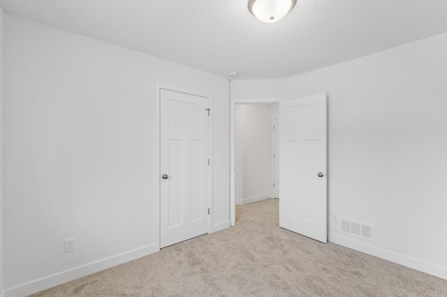 unfurnished bedroom with carpet floors, baseboards, and visible vents