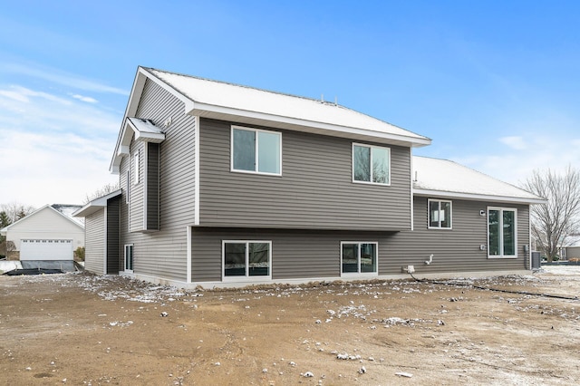 back of property with a detached garage, central AC unit, and an outdoor structure