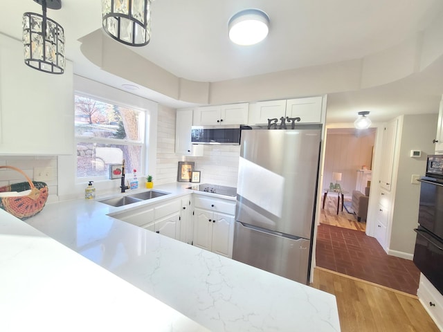 kitchen with hanging light fixtures, white cabinets, appliances with stainless steel finishes, and sink