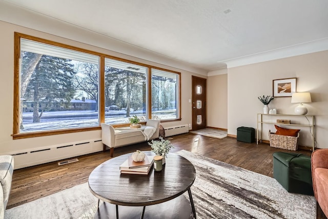 living room featuring baseboard heating, ornamental molding, and hardwood / wood-style floors