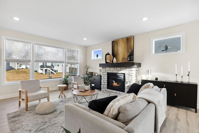 living room with light wood-type flooring and a stone fireplace