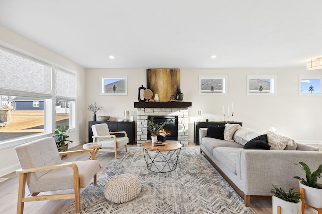 living room featuring a stone fireplace and light hardwood / wood-style floors