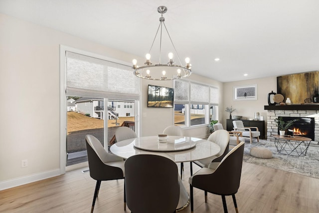 dining area with light hardwood / wood-style flooring, a stone fireplace, and a healthy amount of sunlight