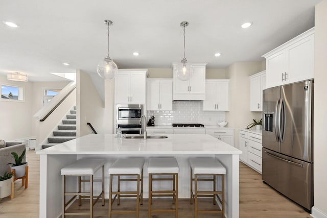 kitchen featuring backsplash, stainless steel appliances, white cabinetry, and sink