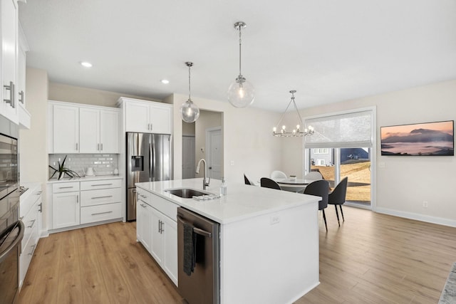 kitchen featuring white cabinetry, sink, hanging light fixtures, a kitchen island with sink, and appliances with stainless steel finishes