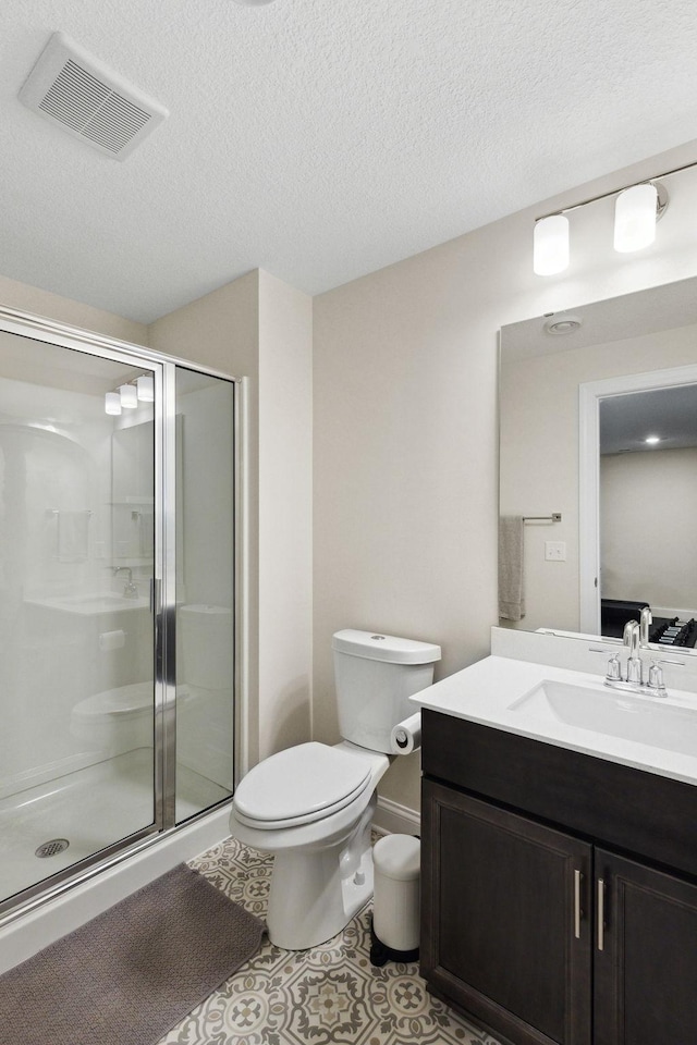 bathroom with a textured ceiling, vanity, tile patterned flooring, toilet, and a shower with shower door