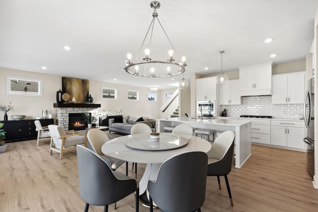 dining room featuring a fireplace, light hardwood / wood-style floors, and a chandelier