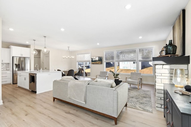 living room with a chandelier, light hardwood / wood-style floors, plenty of natural light, and sink