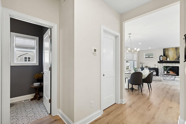 hallway with a notable chandelier and light wood-type flooring