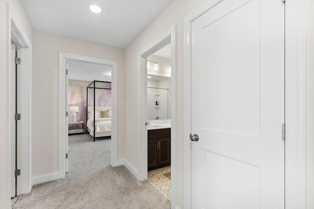 corridor with sink and light colored carpet