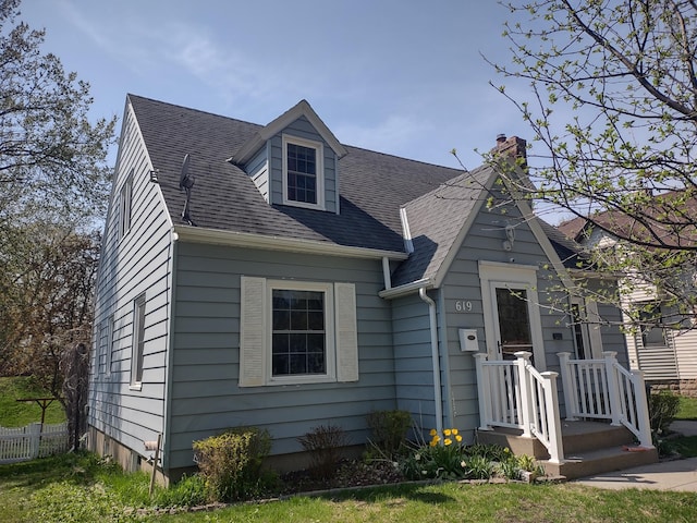 view of front facade featuring a chimney and roof with shingles
