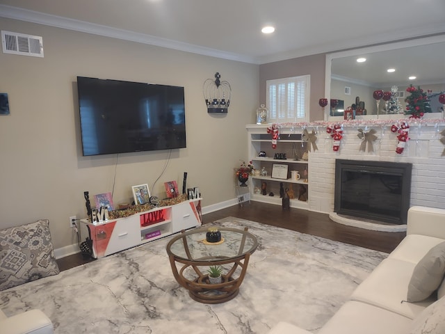 living room featuring wood finished floors, ornamental molding, baseboards, a brick fireplace, and recessed lighting
