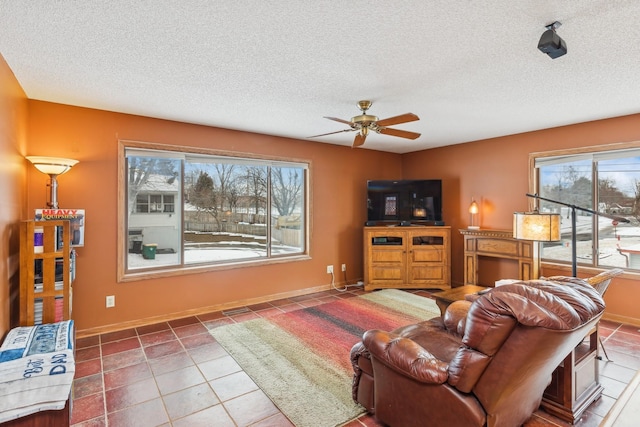 living room featuring tile patterned flooring, ceiling fan, and a textured ceiling