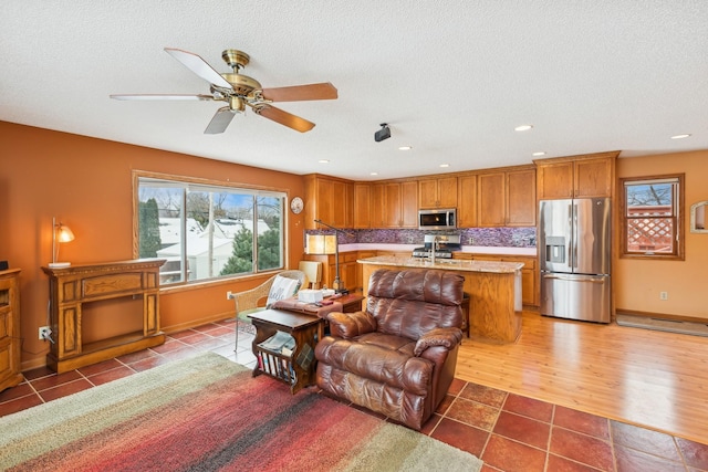 living room with hardwood / wood-style flooring, ceiling fan, and a textured ceiling