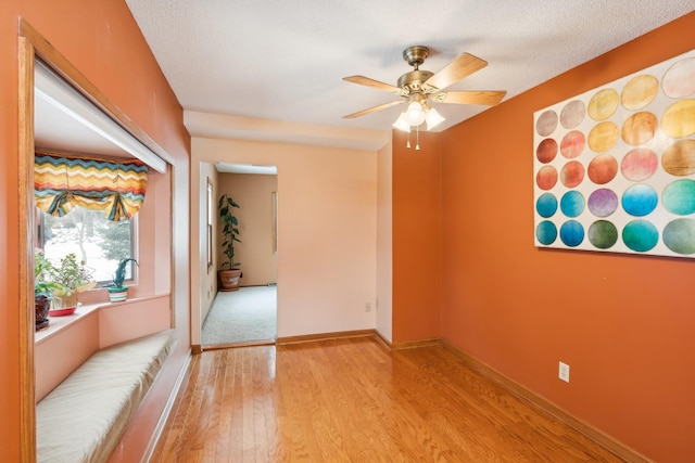 empty room with ceiling fan, light hardwood / wood-style flooring, and a textured ceiling