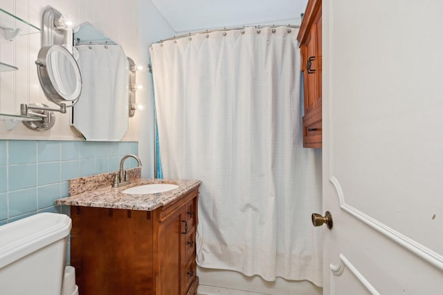 full bathroom with tile walls, decorative backsplash, vanity, toilet, and shower / bath combo with shower curtain