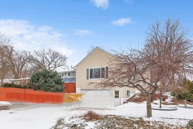 snow covered house featuring a garage