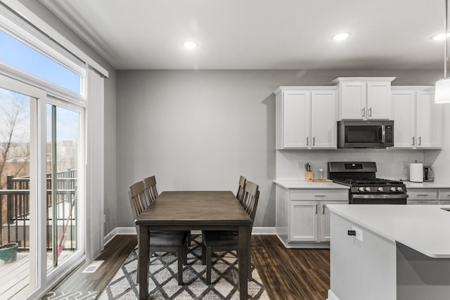 kitchen with decorative backsplash, stainless steel appliances, white cabinetry, and dark wood-type flooring