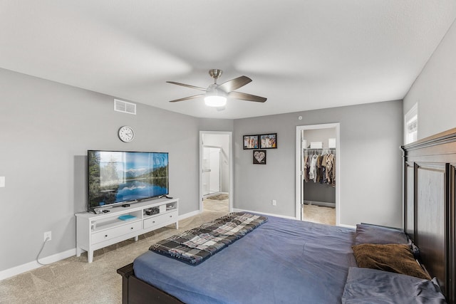 carpeted bedroom with ceiling fan, a walk in closet, and a closet