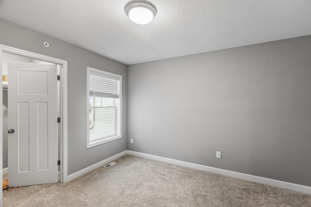 carpeted spare room with a textured ceiling