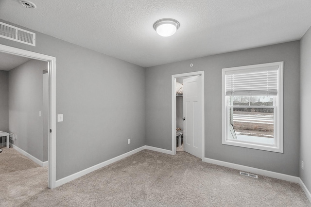 spare room featuring light colored carpet and a textured ceiling