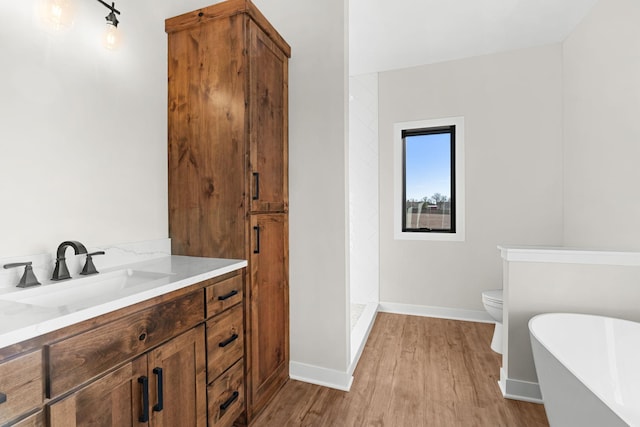 bathroom with toilet, a bathtub, vanity, and hardwood / wood-style flooring