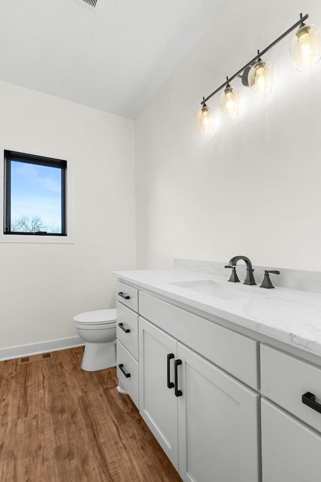 bathroom with toilet, vanity, and hardwood / wood-style flooring