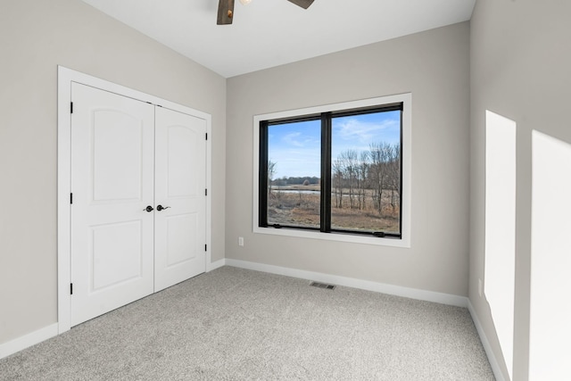 unfurnished bedroom with ceiling fan, light colored carpet, and a closet