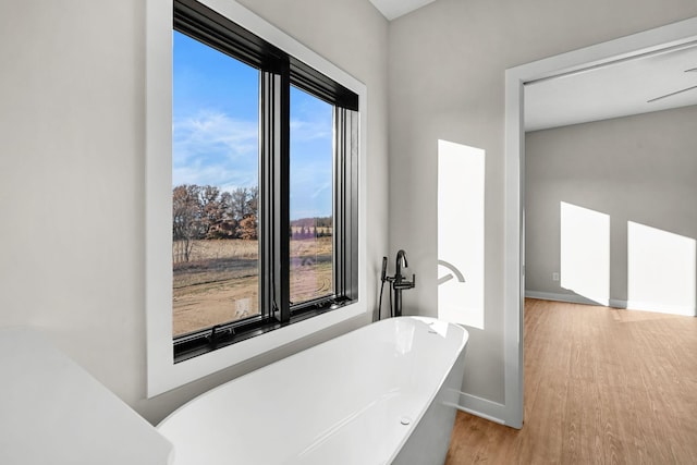 bathroom with hardwood / wood-style floors, a tub to relax in, and a wealth of natural light