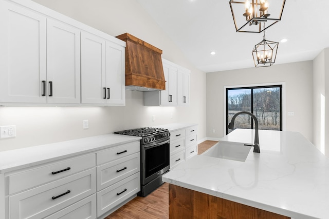 kitchen with sink, an island with sink, decorative light fixtures, and stainless steel gas range