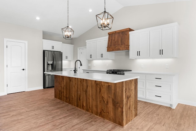 kitchen with light hardwood / wood-style flooring, stainless steel fridge, an island with sink, a chandelier, and white cabinets