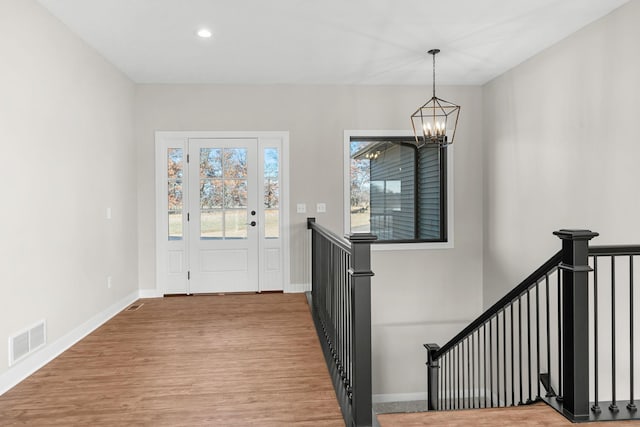 foyer featuring hardwood / wood-style floors, a notable chandelier, and a healthy amount of sunlight