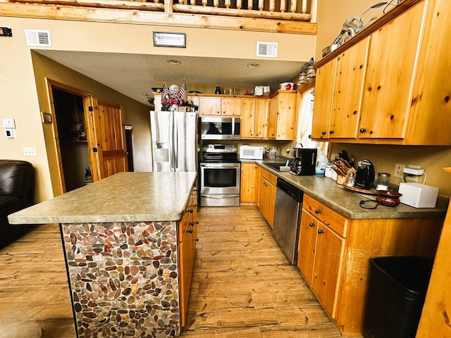 kitchen with a center island, sink, light hardwood / wood-style flooring, a textured ceiling, and stainless steel appliances