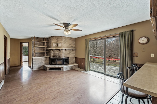 living room with ceiling fan, plenty of natural light, a textured ceiling, and wooden walls