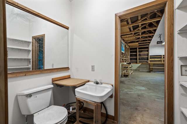 bathroom featuring sink, concrete flooring, and toilet