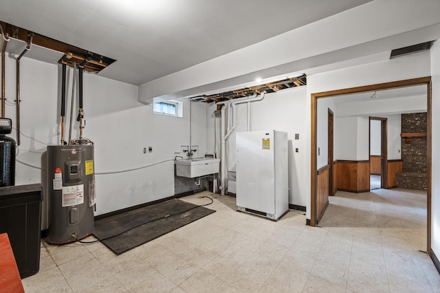 basement with electric water heater, wooden walls, sink, and white refrigerator