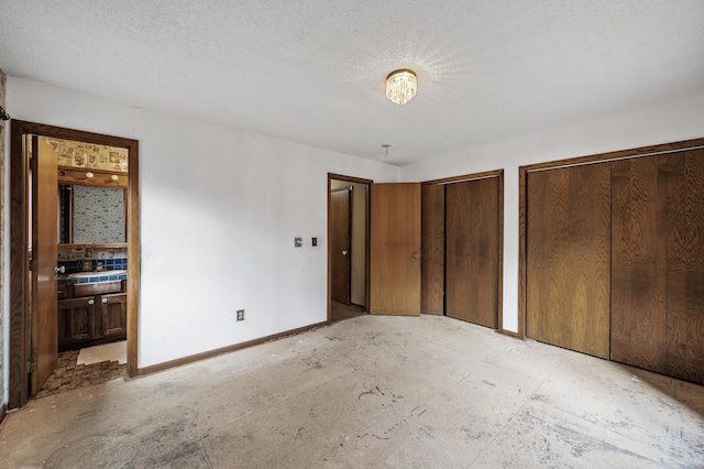 unfurnished bedroom featuring connected bathroom, multiple closets, and a textured ceiling