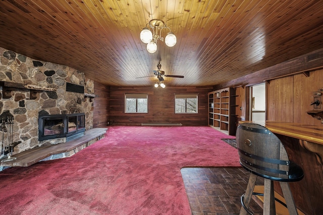 living room with wood walls, a fireplace, and ceiling fan