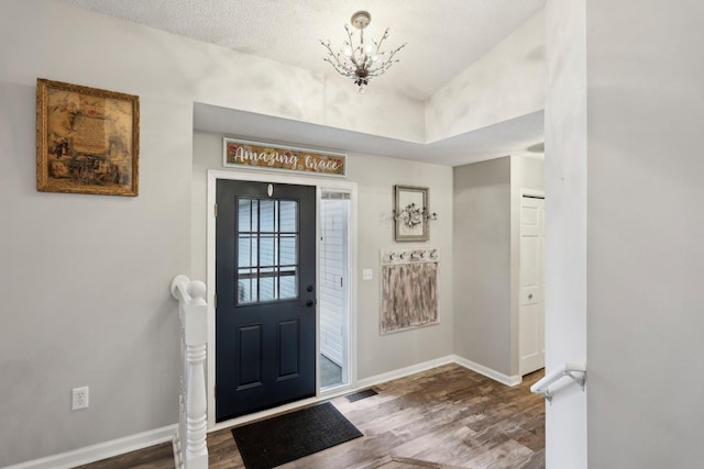 foyer entrance featuring an inviting chandelier, wood-type flooring, and a textured ceiling