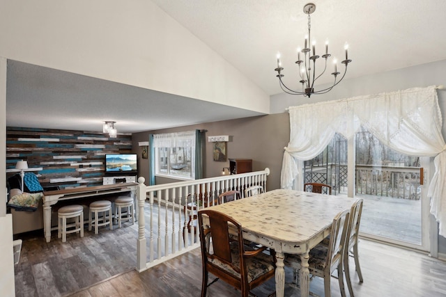 dining room with lofted ceiling, dark hardwood / wood-style floors, a textured ceiling, and an inviting chandelier