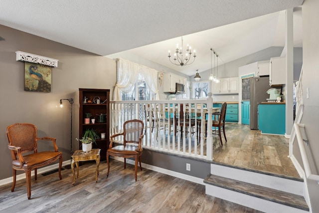 interior space with hardwood / wood-style flooring, lofted ceiling, a notable chandelier, and a textured ceiling