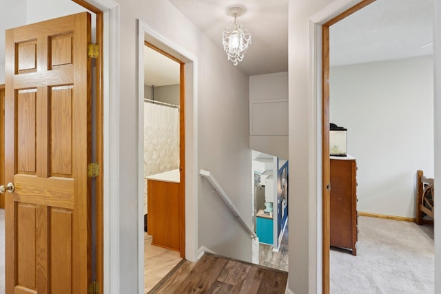 hallway featuring an inviting chandelier and light hardwood / wood-style floors