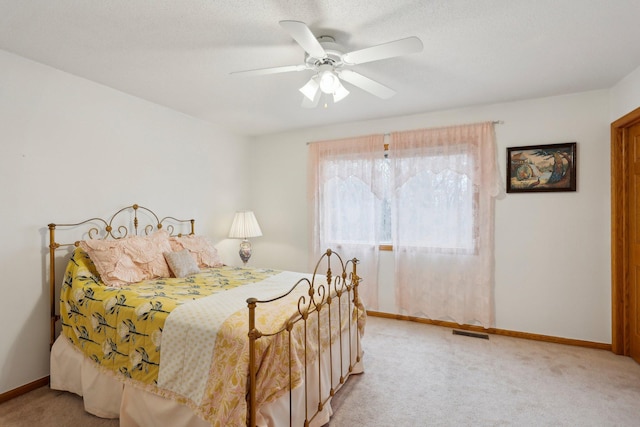 carpeted bedroom with ceiling fan and a textured ceiling