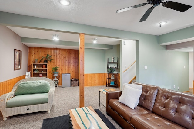 living room featuring carpet flooring, ceiling fan, and wood walls