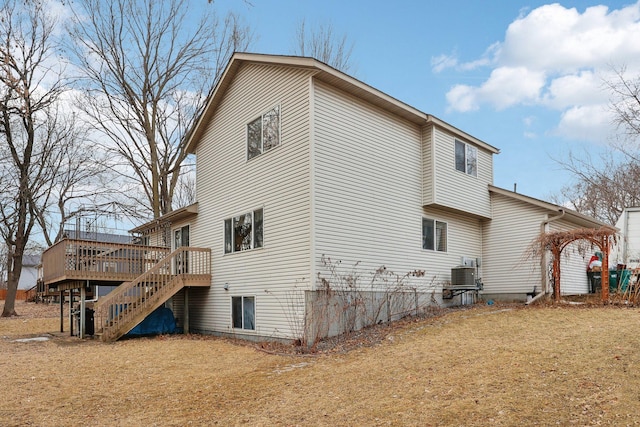 view of property exterior with a deck, central AC unit, and a lawn