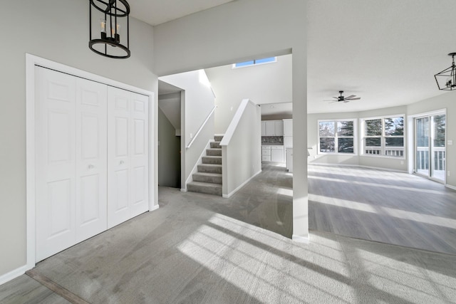 entryway with carpet floors and ceiling fan with notable chandelier