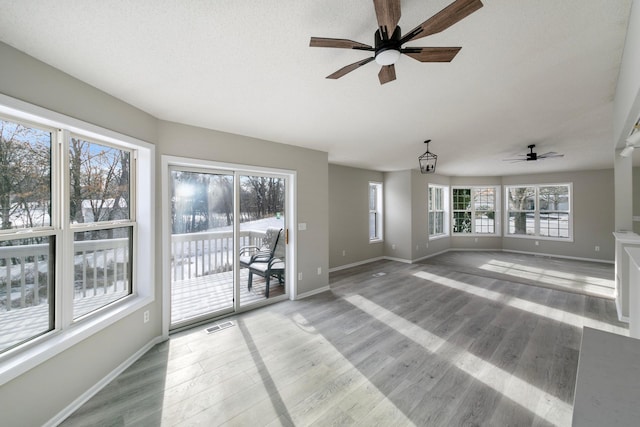 unfurnished living room with ceiling fan with notable chandelier, wood-type flooring, and a textured ceiling