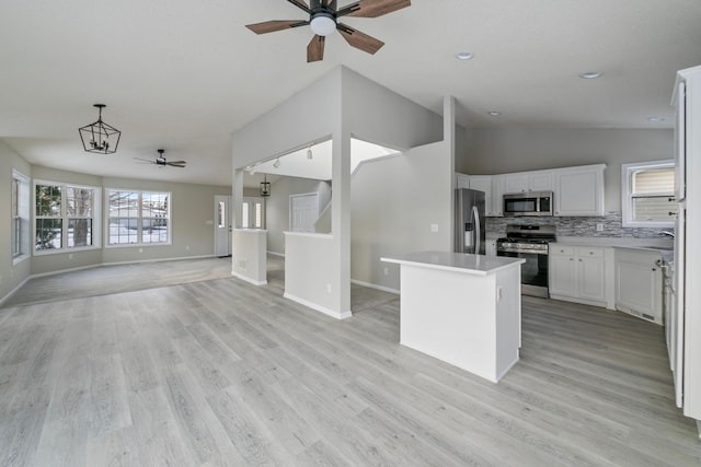 kitchen featuring a center island, white cabinetry, stainless steel appliances, tasteful backsplash, and hanging light fixtures