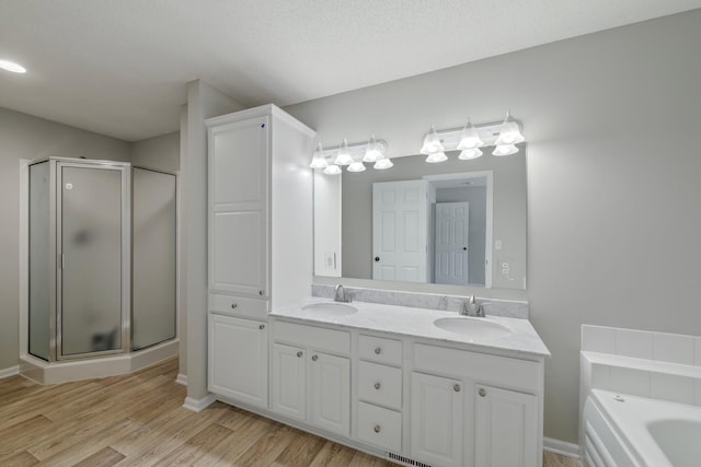 bathroom with vanity, wood-type flooring, independent shower and bath, and a textured ceiling