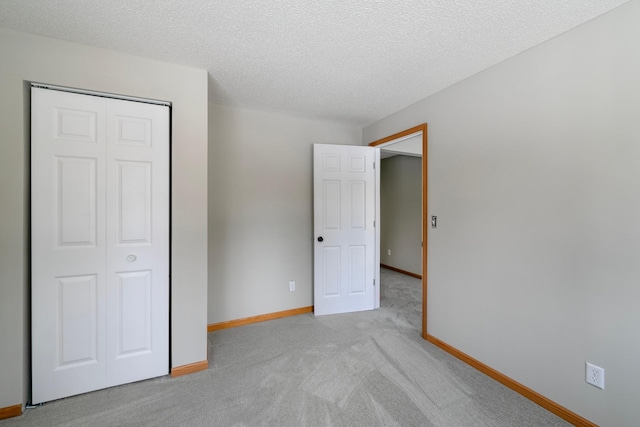 unfurnished bedroom with light carpet, a closet, and a textured ceiling